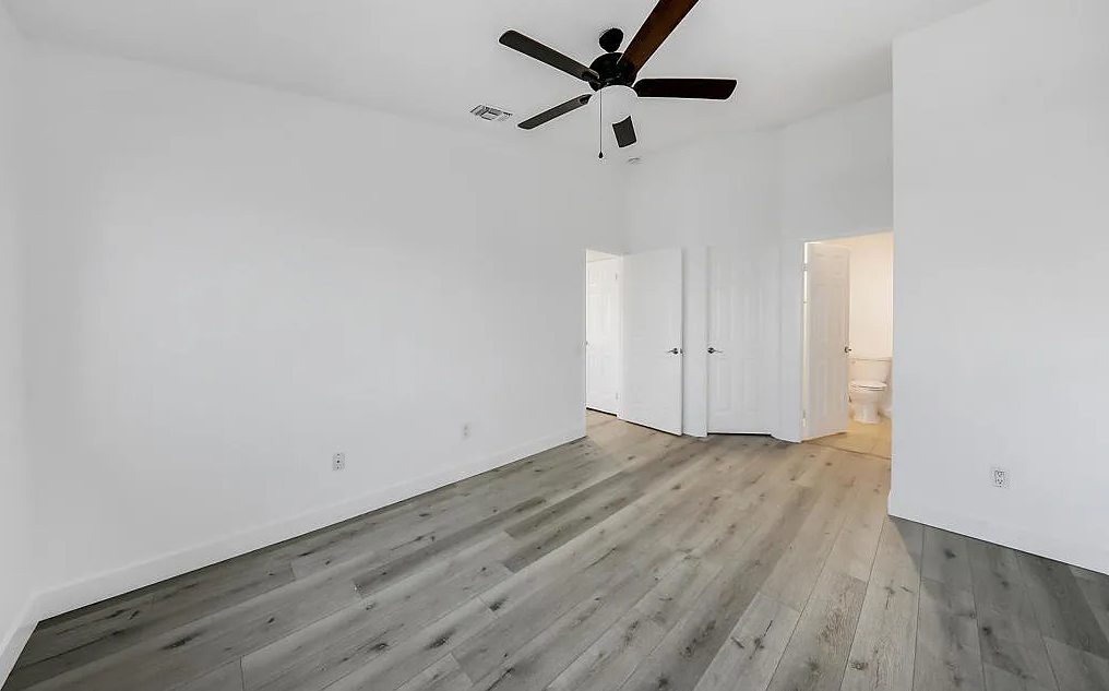 a bedroom with white walls and a ceiling fan