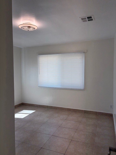 A room with a window covered by white blinds and a light on the ceiling.