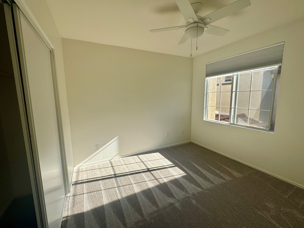 A room with a carpeted floor and a ceiling fan.