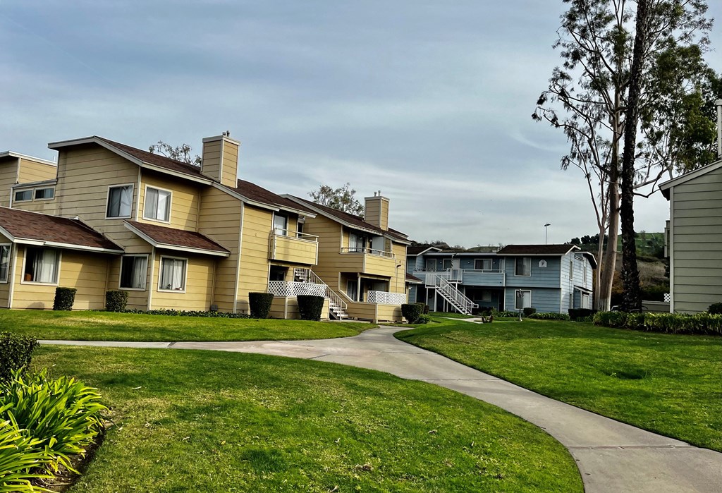 a row of houses on a grassy hill with a cloudy sky in the background