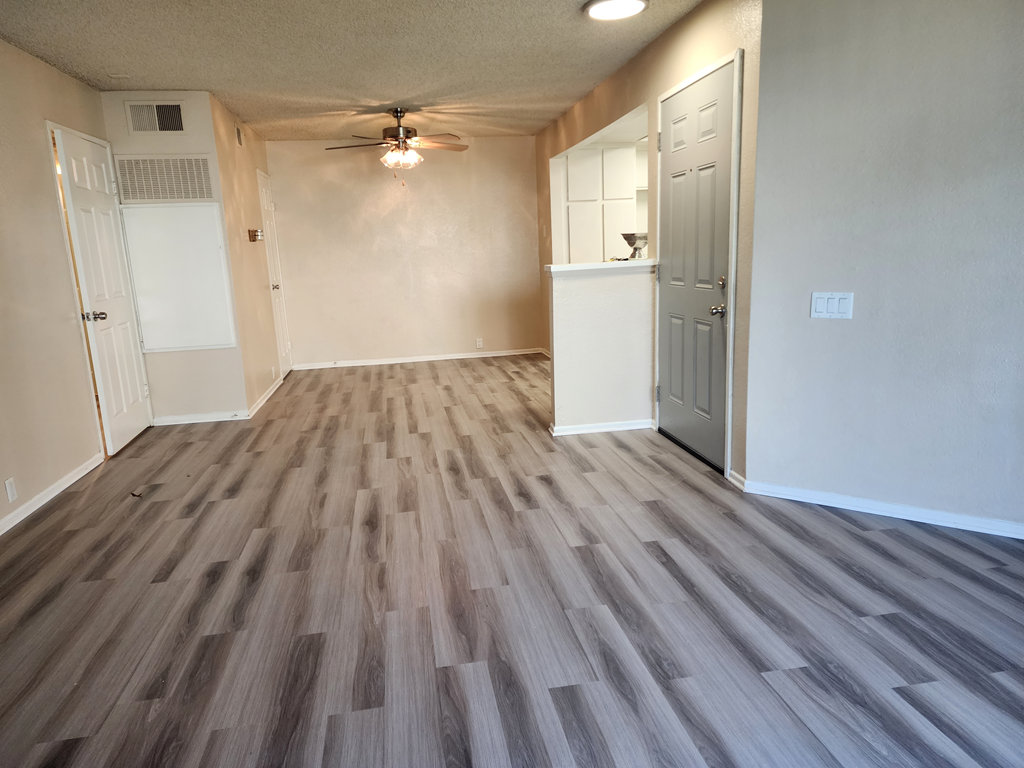 an empty living room with hardwood floors and a ceiling fan