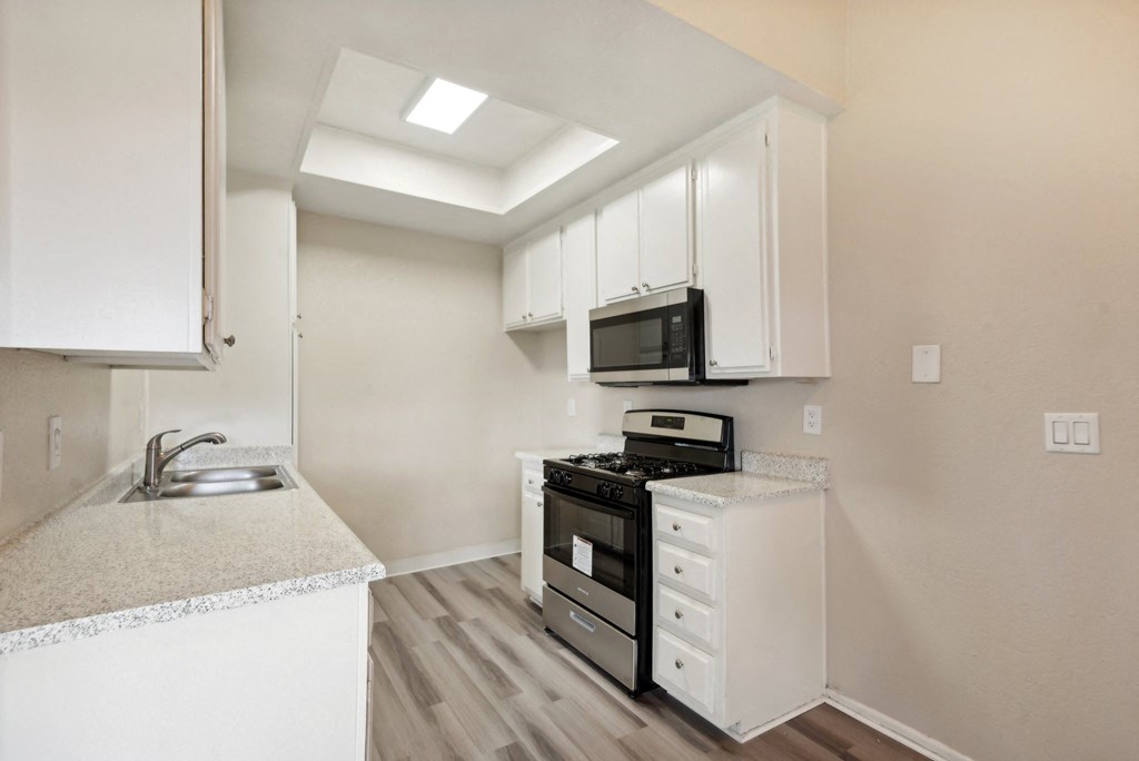 an empty kitchen with white cabinets and a black stove