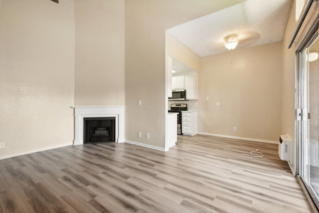 an empty living room with a fireplace and a kitchen