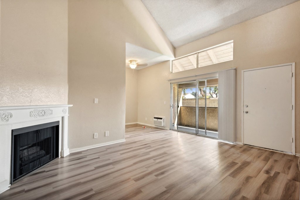 an empty living room with a fireplace and sliding glass doors
