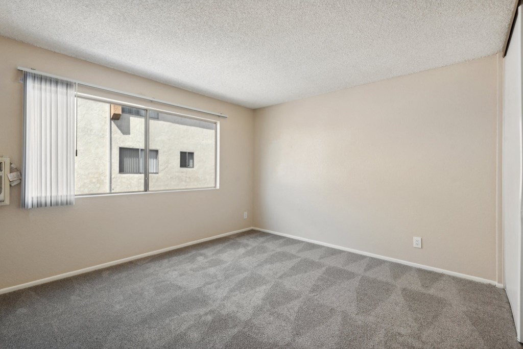 the spacious living room of an apartment with a large window