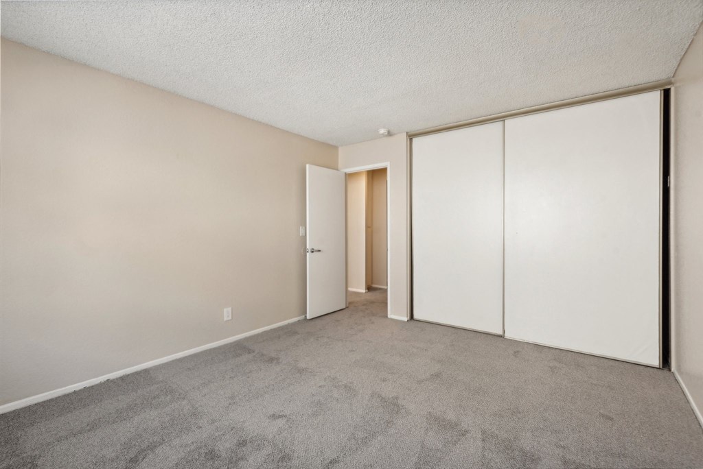 an empty living room with white walls and a door to a closet