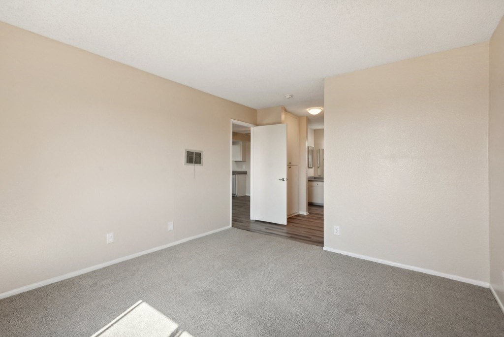 the living room of an apartment with carpet and white walls