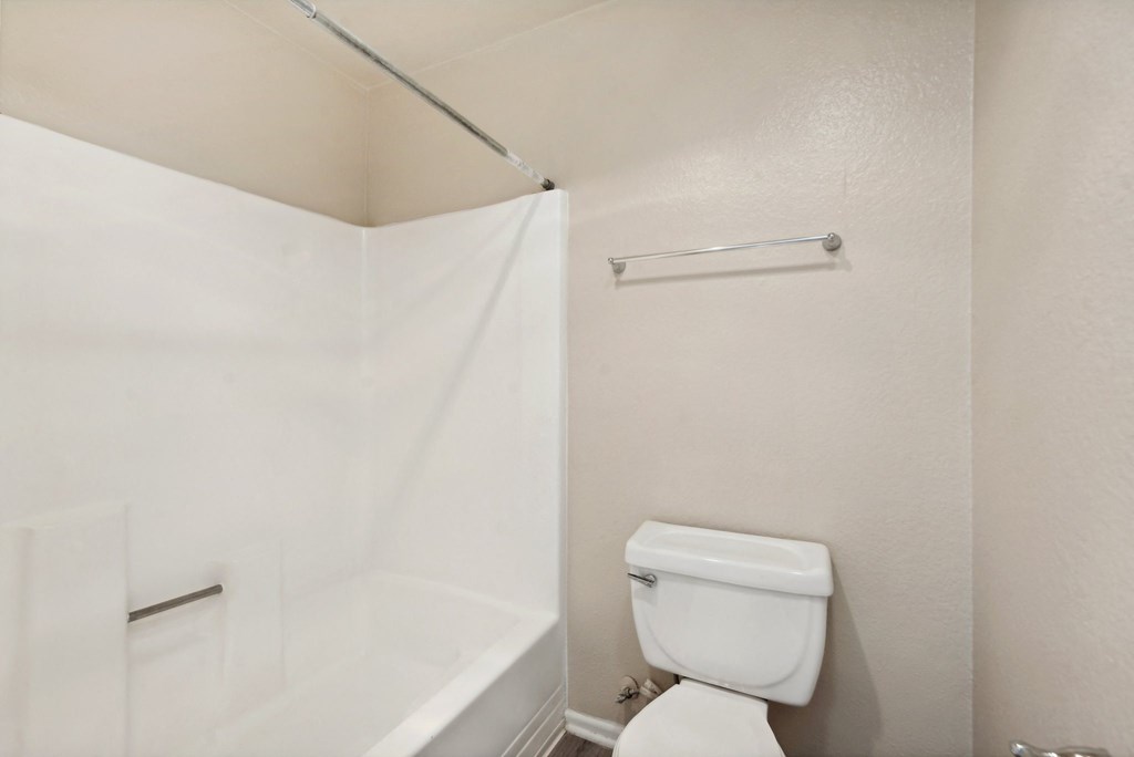 a bathroom with a toilet and a tub and a shower