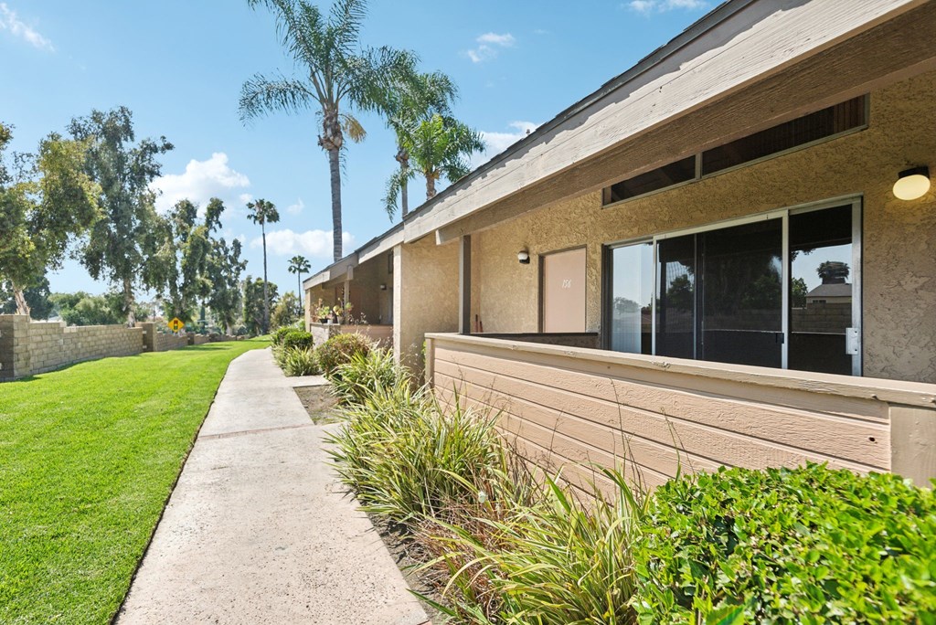 the side of a building with a sidewalk and grass