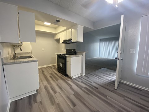 A kitchen area with a sink, stove, and cabinets.