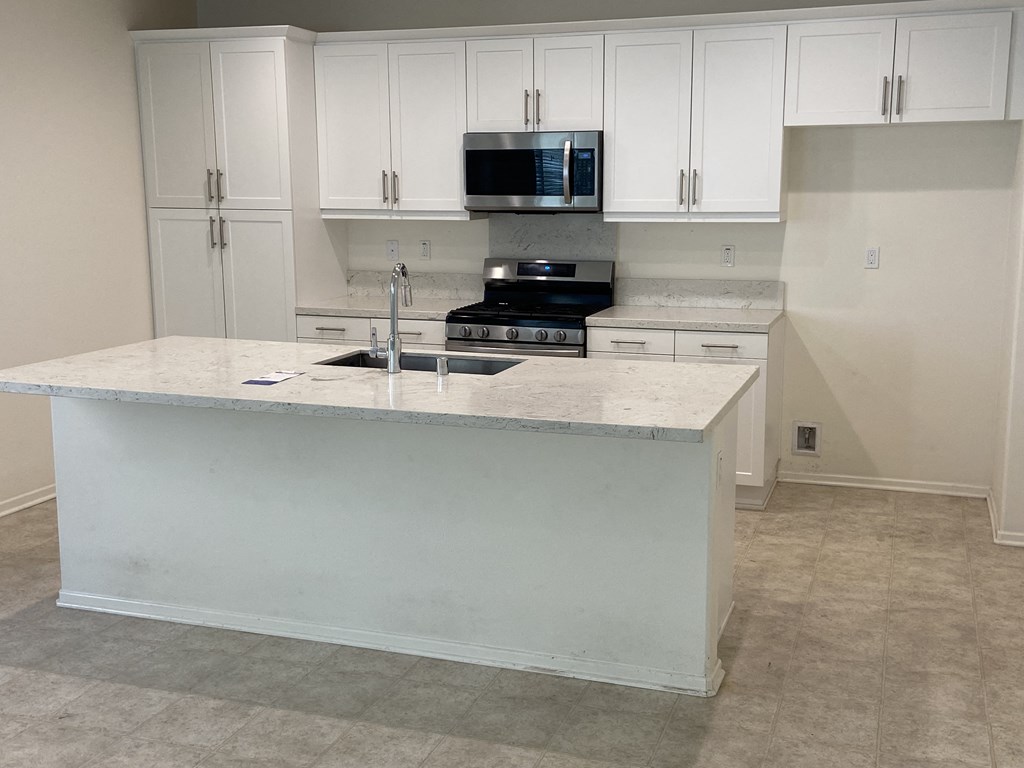 an empty kitchen with white cabinets and a counter top