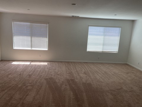 an empty living room with wood floors and two windows