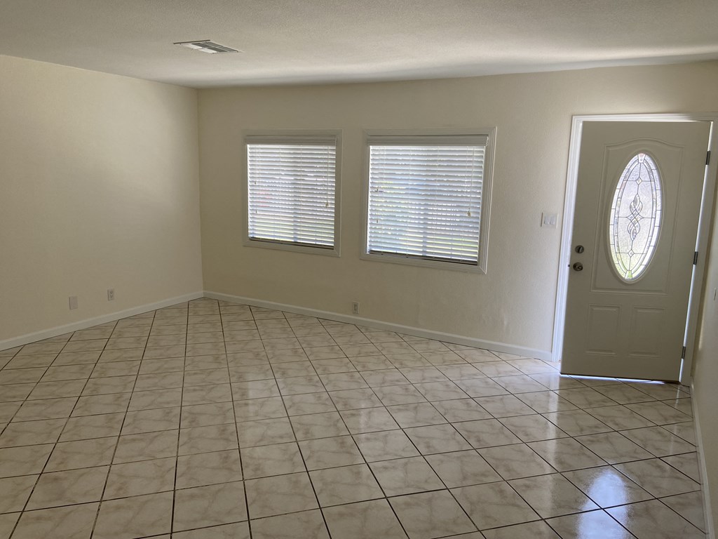 an empty living room with a door and three windows