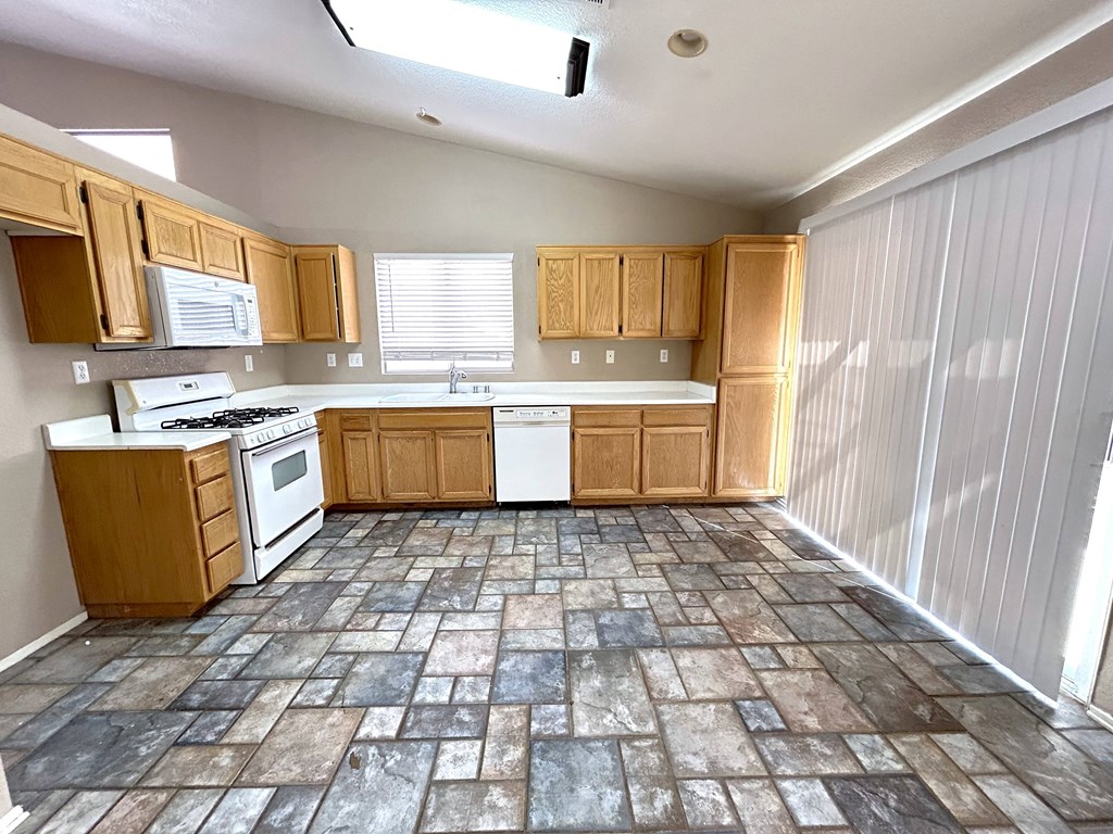 A kitchen with wooden cabinets and a tiled floor.