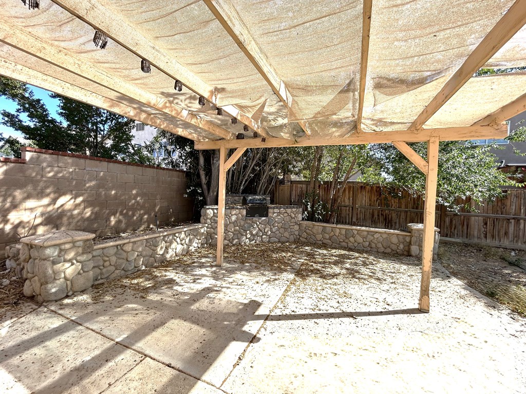 A patio with a white canopy and a stone wall.