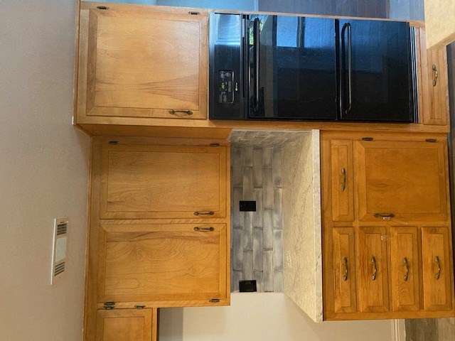 a kitchen with wooden cabinets and a black refrigerator