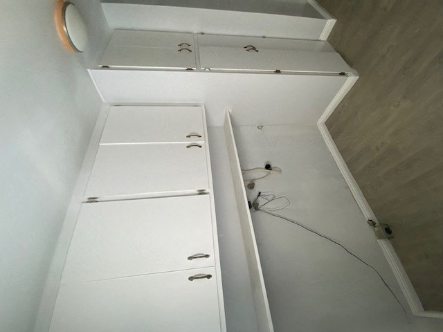 a white closet with white drawers and some wires on the floor