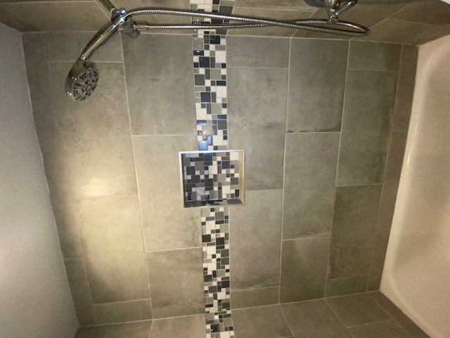 a tiled shower with a shower head in a bathroom
