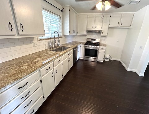 A kitchen with white cabinets and a granite countertop.