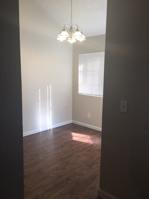 A room with a chandelier and a window with blinds.