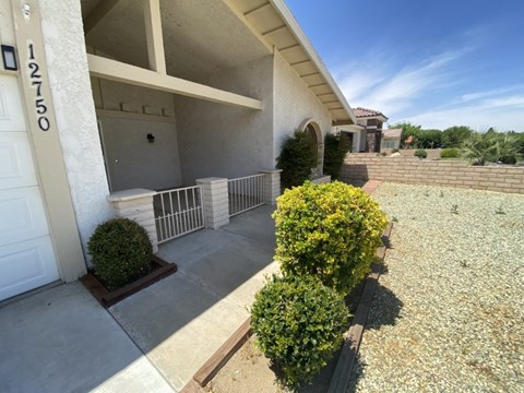 A house numbered 12750 with a white garage door and a small garden in front.