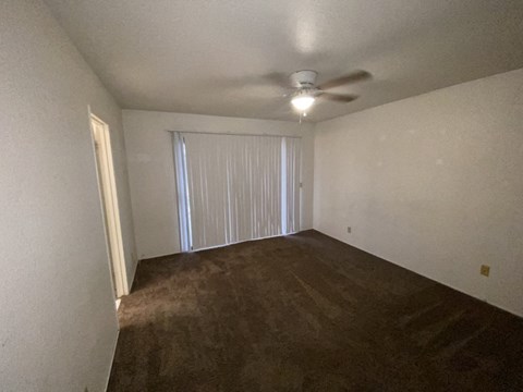 an empty living room with a ceiling fan