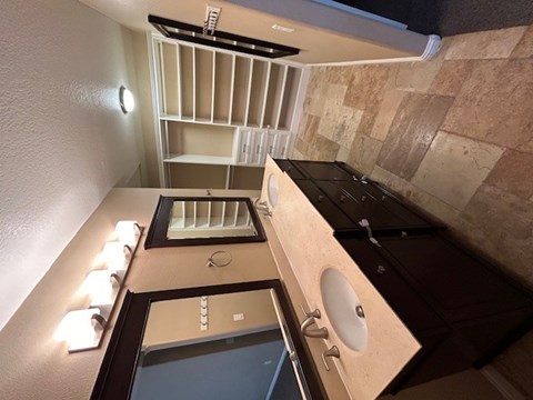 A bathroom with a sink, mirror, and lighting fixtures.