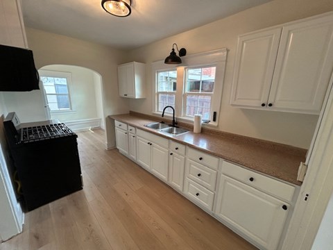 A kitchen with white cabinets and a black fridge.