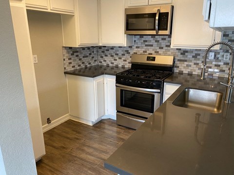 A kitchen with a black stove top oven and a black microwave above it.