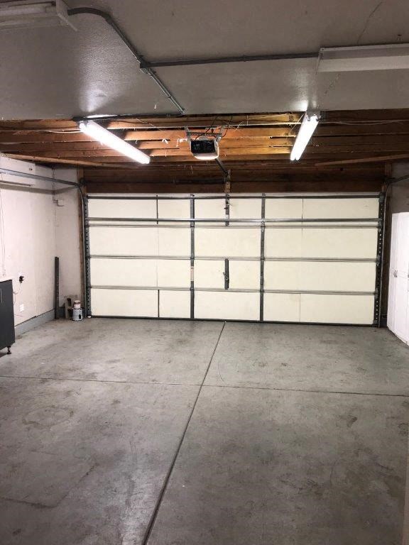 A large garage with a white door and a wooden ceiling.