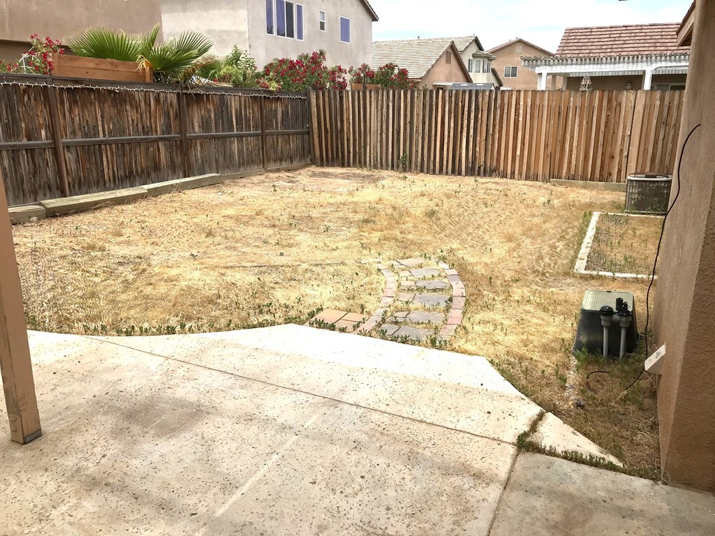 A backyard with a wooden fence and a small garden.