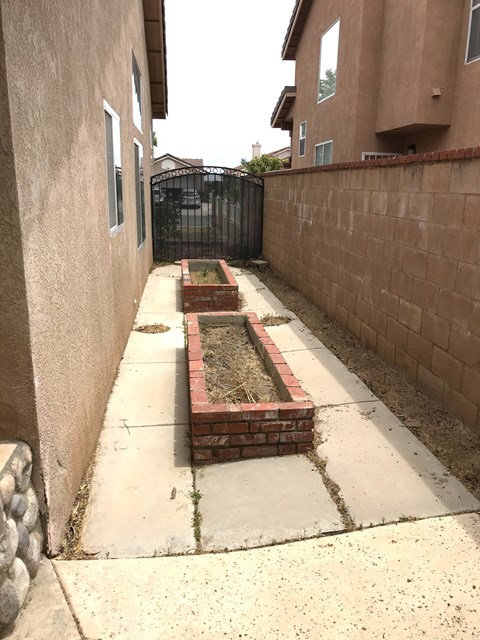 A long concrete walkway leads to a brick planter box.