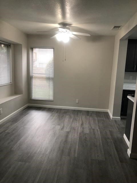 A room with a ceiling fan and a window with blinds.