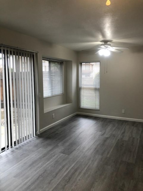 A room with a ceiling fan and sliding glass doors.