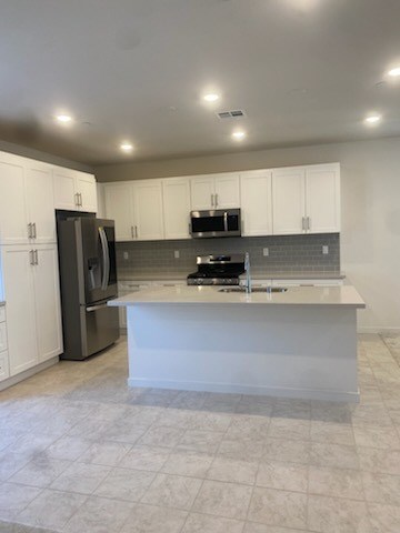 A kitchen with white cabinets and a white island.