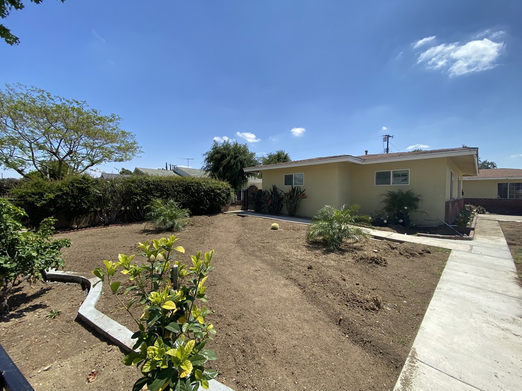 A backyard with a dirt area and a concrete walkway.