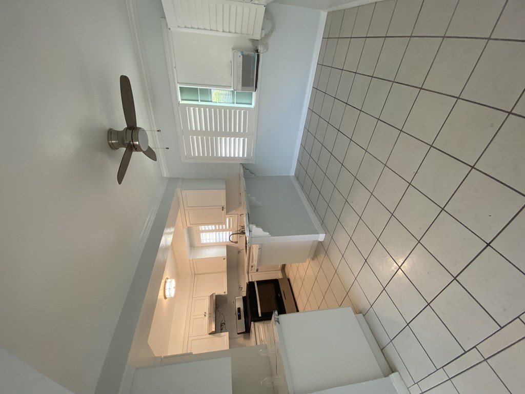 A white tiled staircase with a fan on the wall.