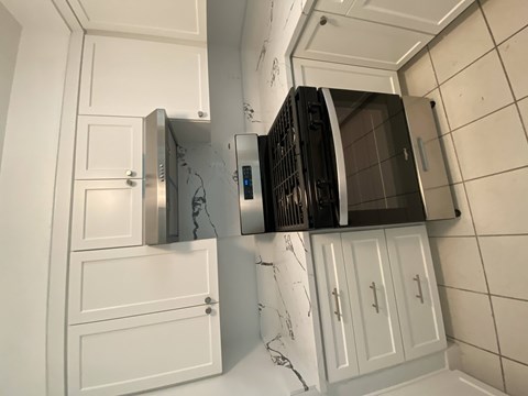 A kitchen with white cabinets and a black oven.