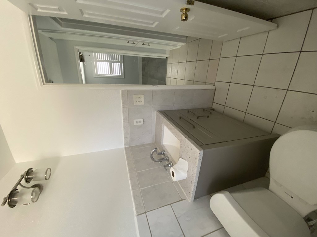 A bathroom with a toilet, sink, and mirror.