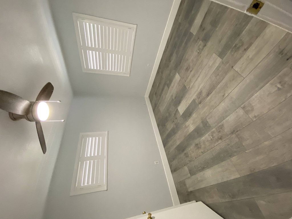 A ceiling fan is on the left side of a room with a wooden ceiling.