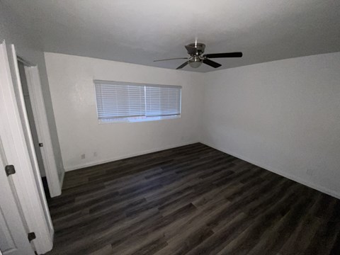 A room with a ceiling fan and a window with blinds.