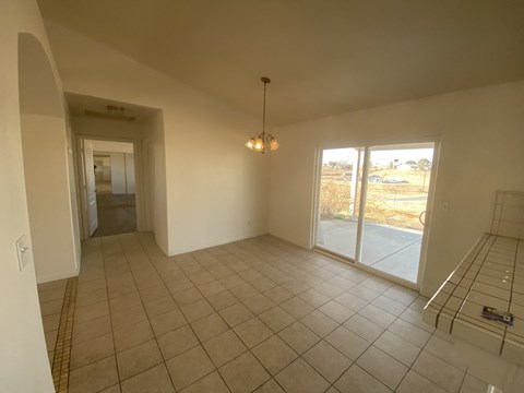 A large empty room with a tiled floor and a chandelier hanging from the ceiling.