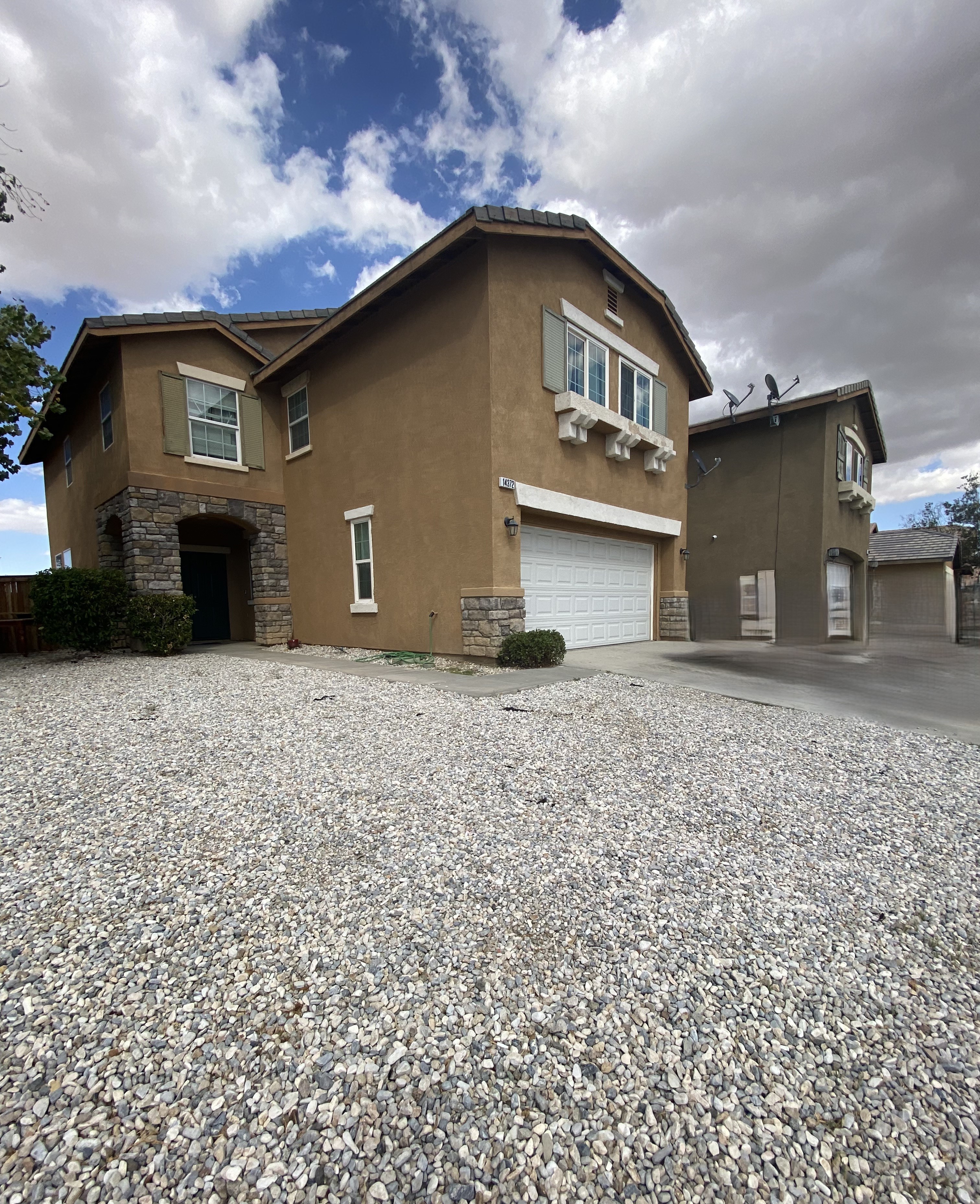A house with a gravel driveway in front.
