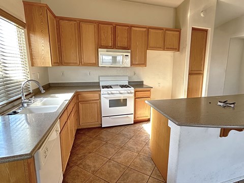 A kitchen with wooden cabinets and a white stove top oven.