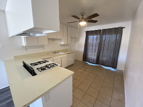 A kitchen with a white countertop and a black stove top.