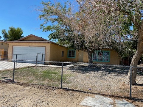 A yellow house with a grey garage door and a fence.