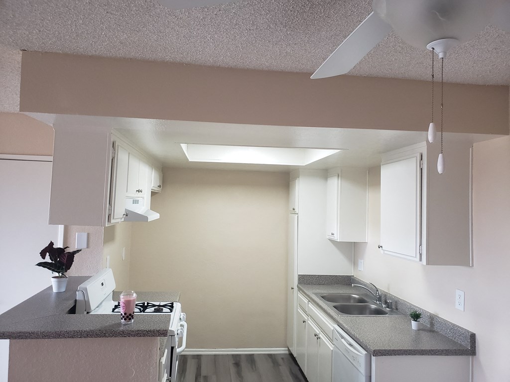 a kitchen with white cabinets and a ceiling fan