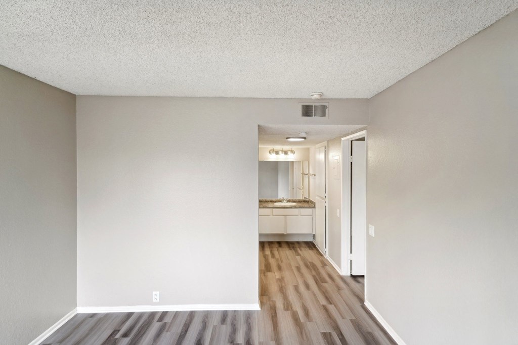 the living room of an apartment with wooden floors and white walls