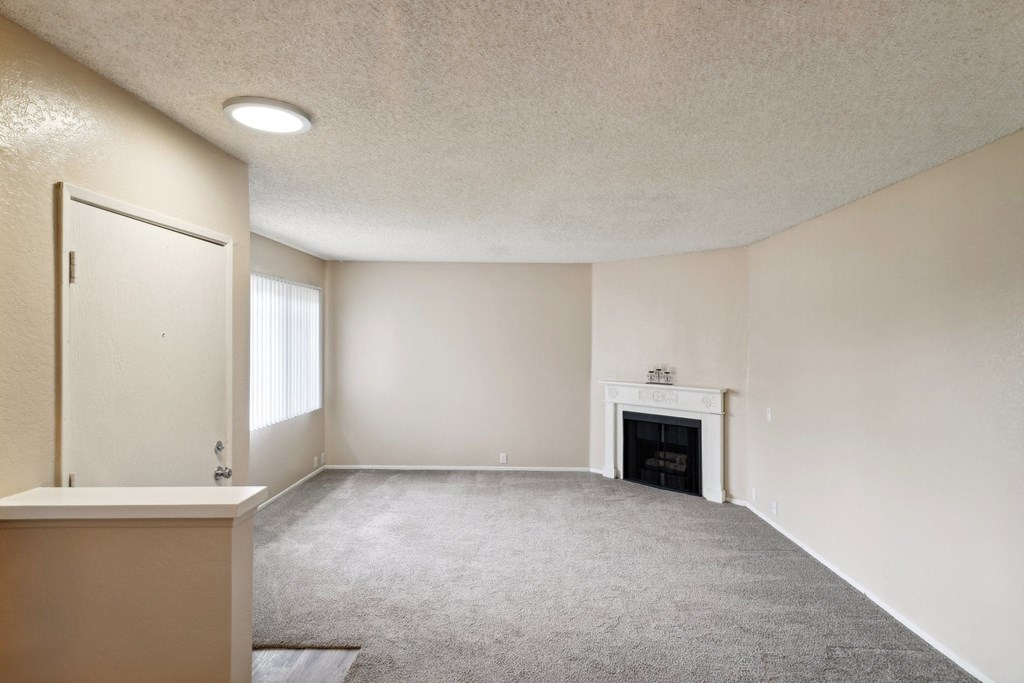 an empty living room with a fireplace and a window