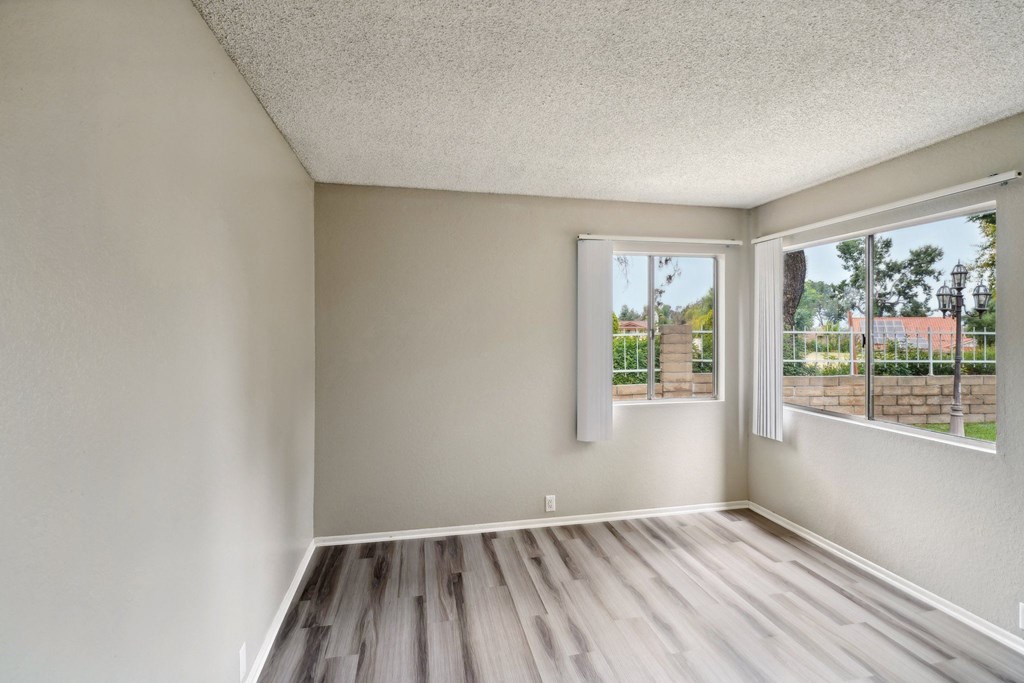 an empty living room with a large window and wooden floors